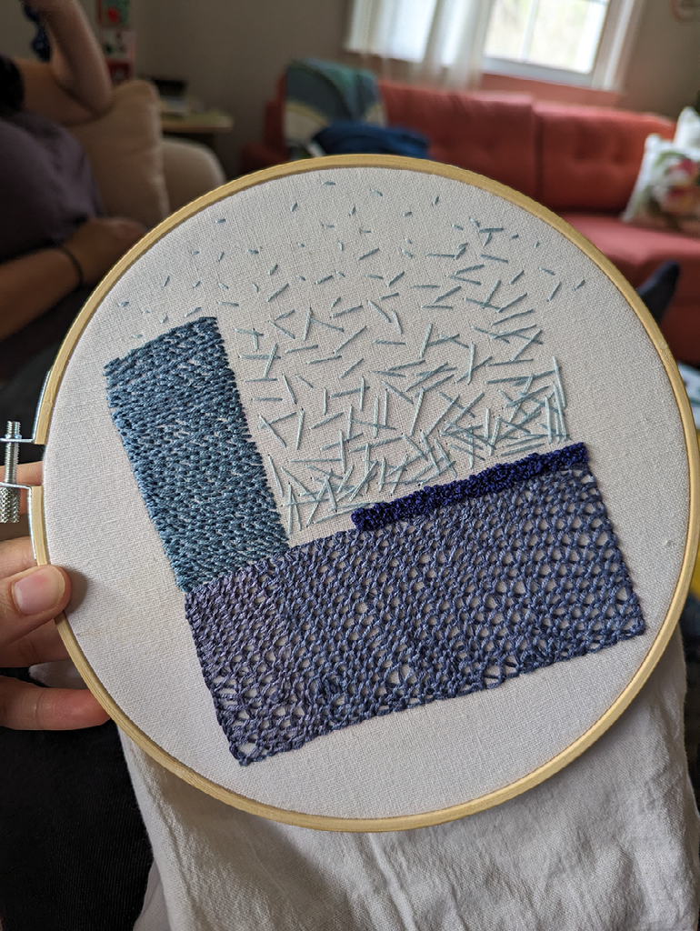 Light blue seed stitches are short and far apart toward the edge of the embroidery hoop, placed outside of the square shape. The stitches become longer and more densely placed toward the bottom of the square, making the shape clear.
