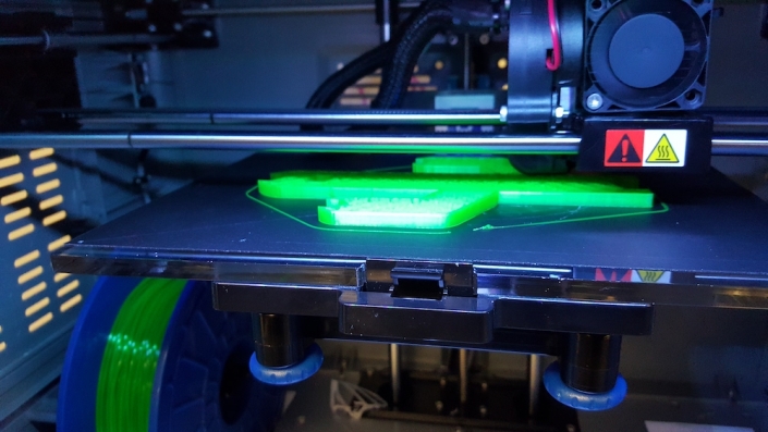 A 3D printer in the middle of printing a neon green item