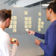 two people adding sticky notes to a diagram